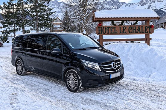 Van Mercedes noir dans la neige devant l’enseigne Hôtel Le Chalet.